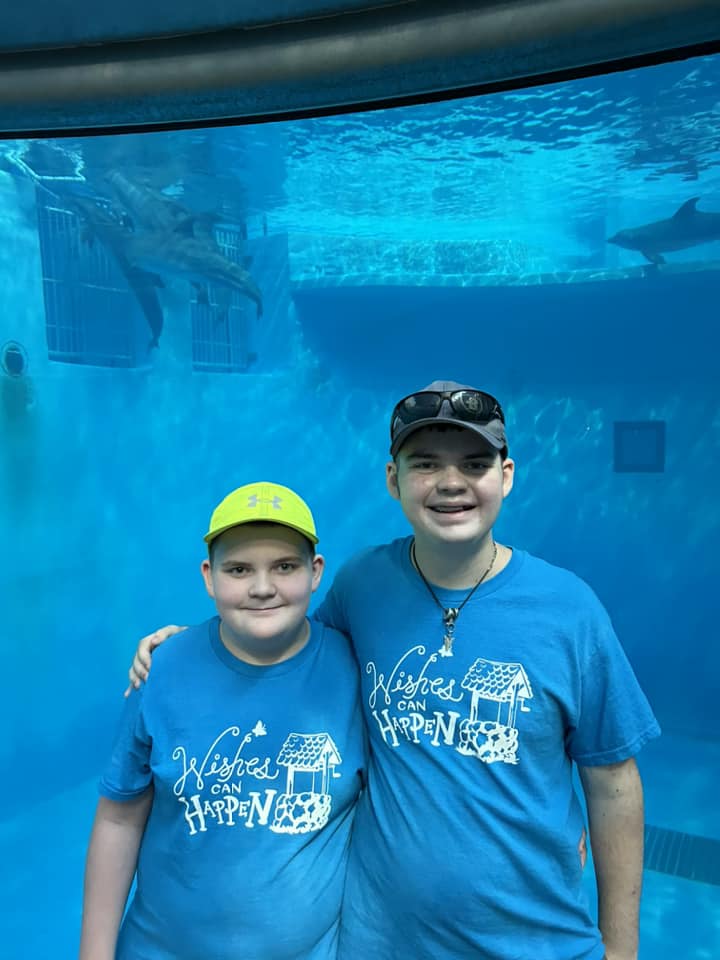 Evan and bro in front of water tank at zoo