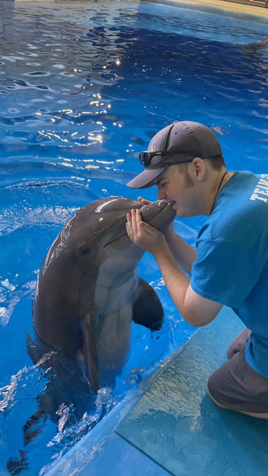 Evan kissing a dolphin